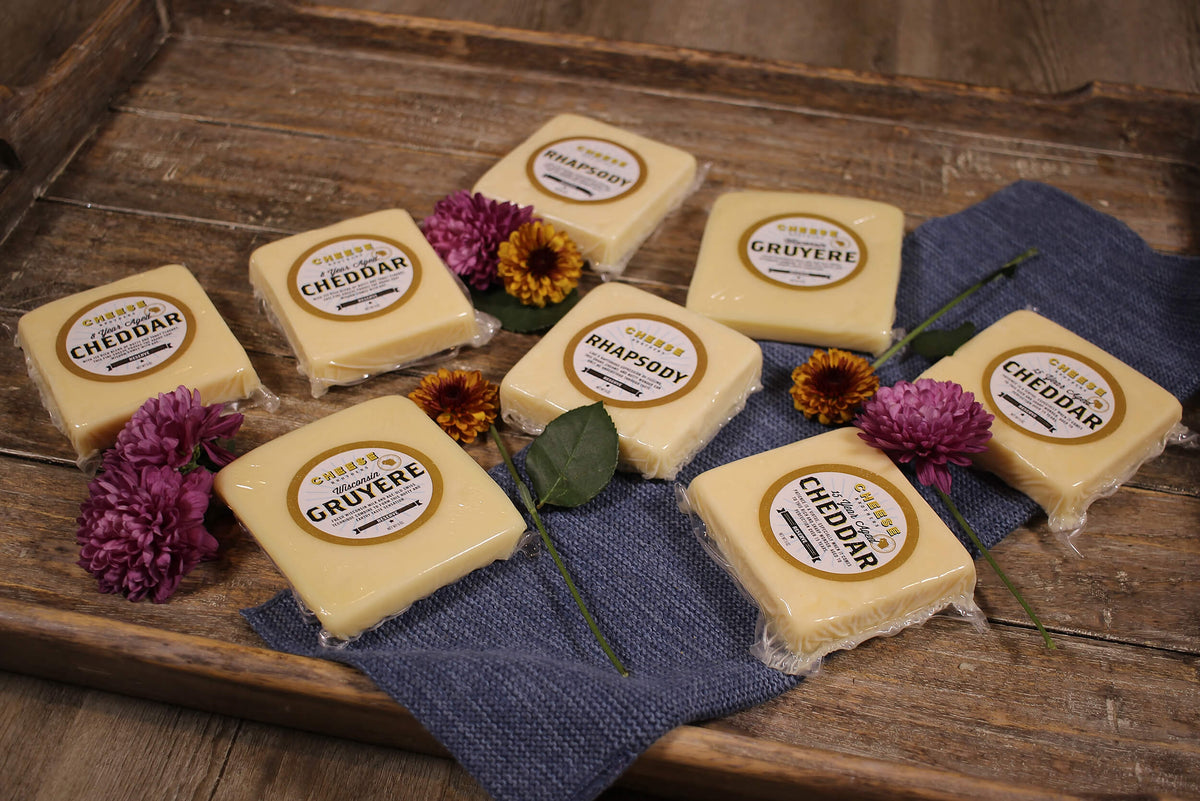 Eight varieties of Wisconsin cheeses from Cheese Brother&#39;s Signature collection on black cloth.
