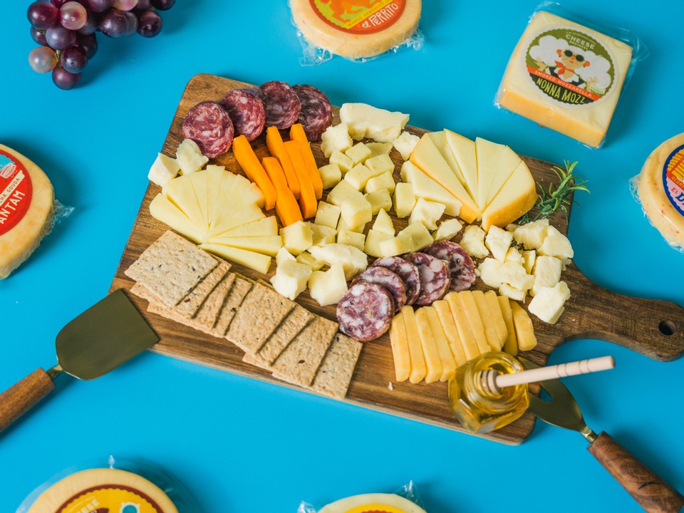 Charcuterie board with a variety of artisan cheeses, honey, crackers, and sausages.
