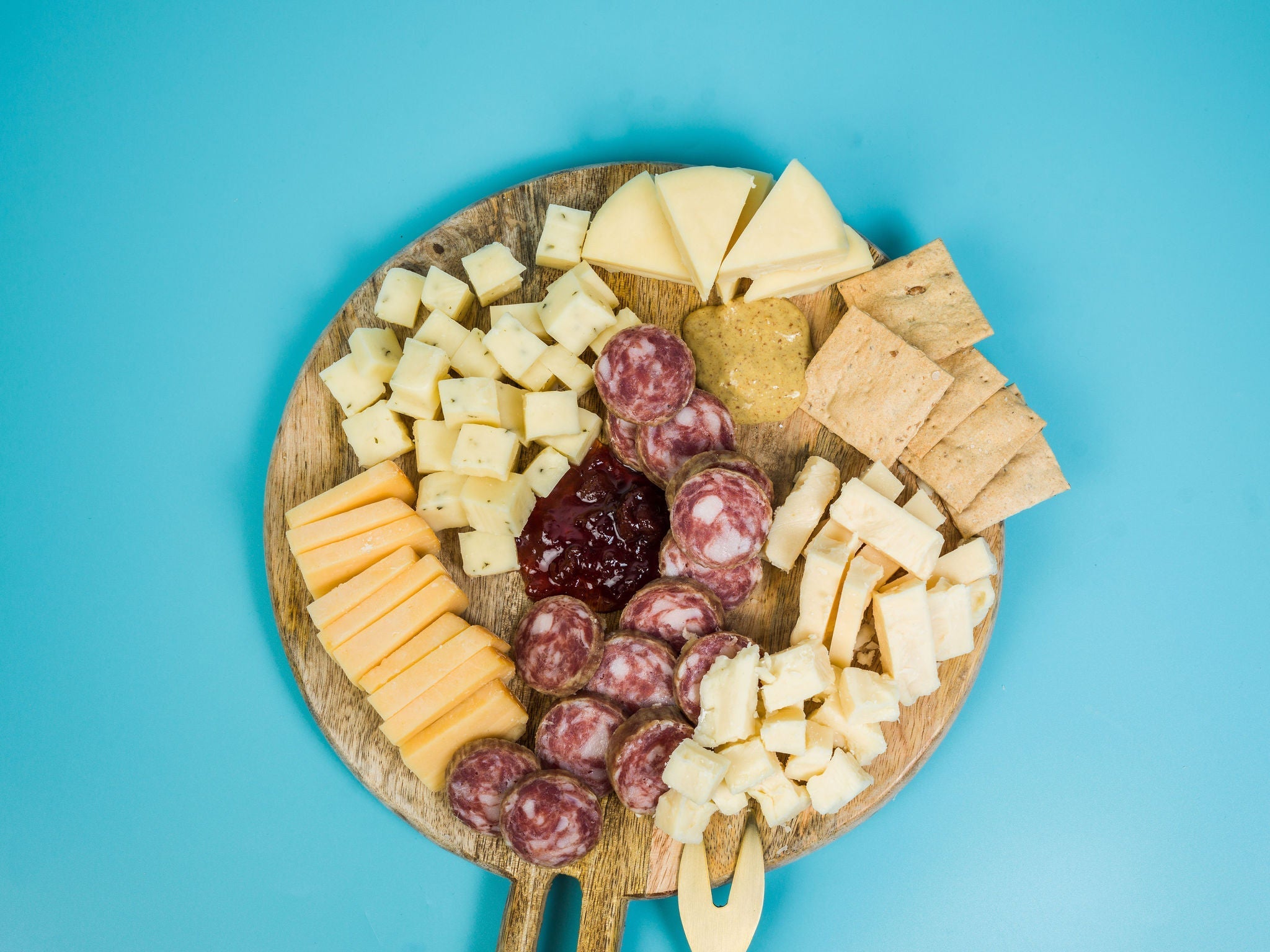 Charcuterie board with artisan Wisconsin cheeses, jam, sausage, mustard, and crackers. 