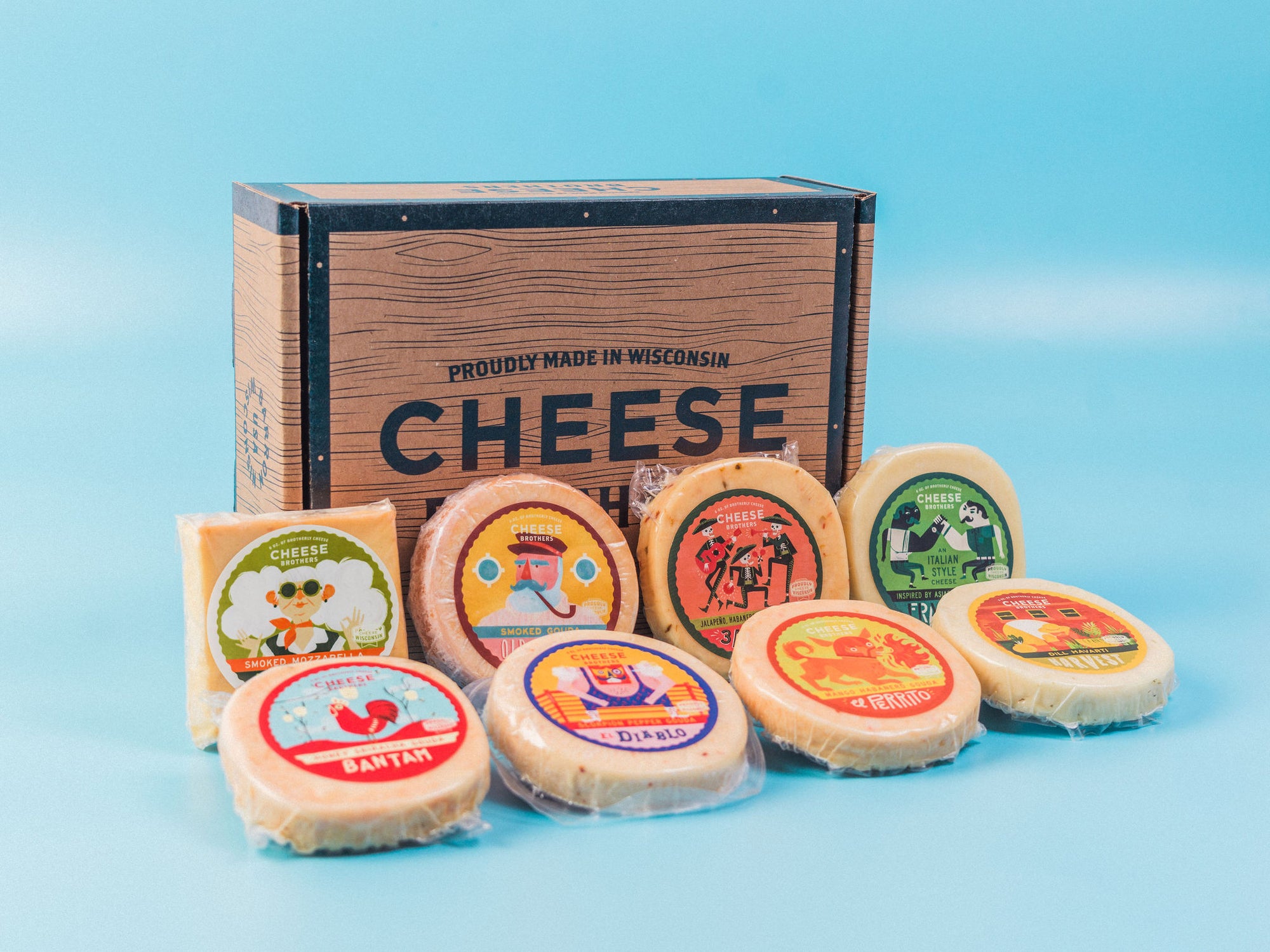 Eight varieties of Wisconsin artisan cheeses in front of Cheese Brothers box. 