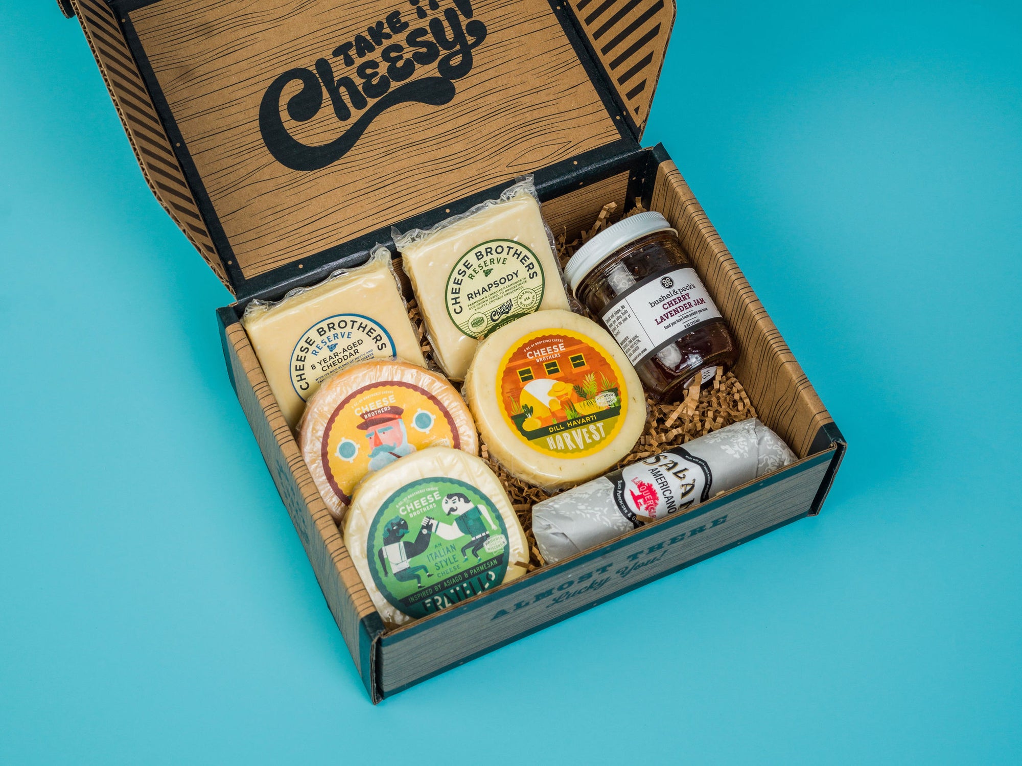 Cheese box with jam, salami, and five varieties of cheeses. 