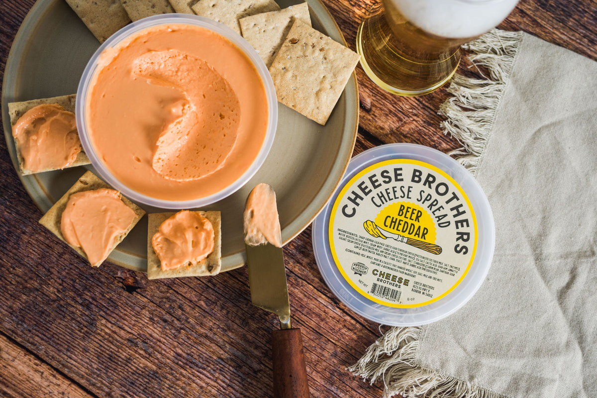 Container of beer cheese spread with crackers and glass of beer. 