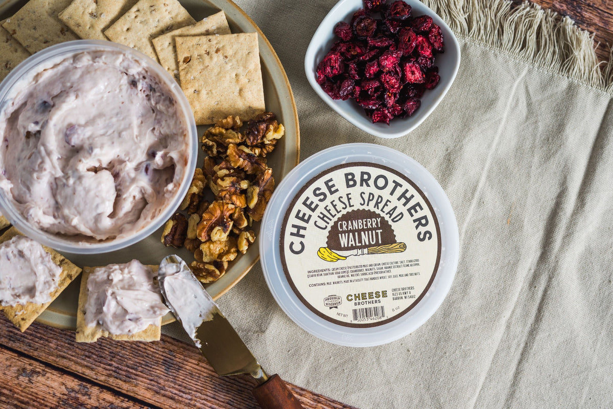 Container of cranberry walnut cheese spread with crackers and bowl of cranberries. 