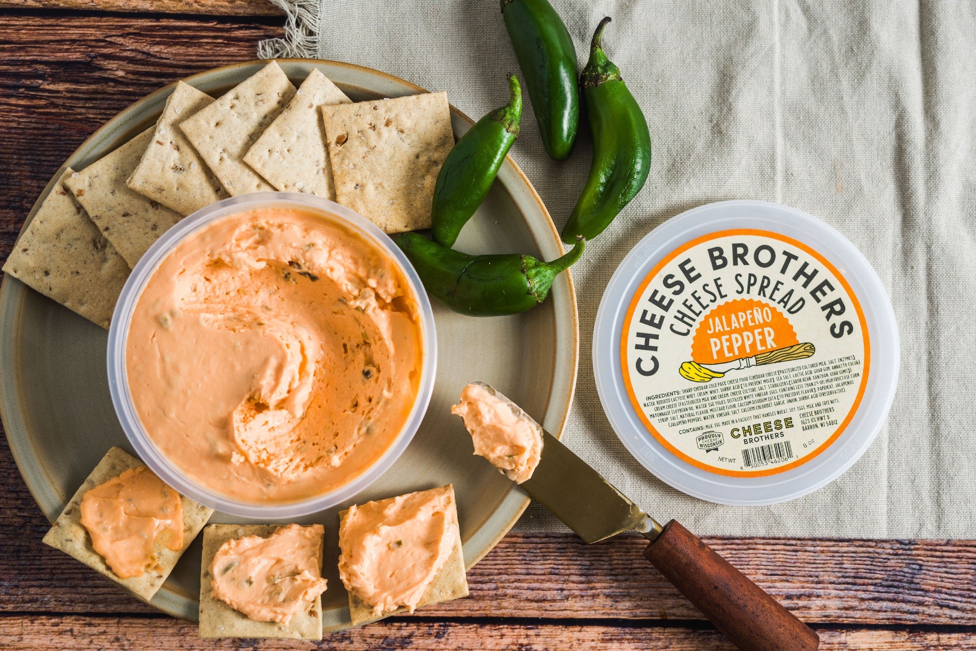 Container of jalapeno pepper cheese spread with crackers. 