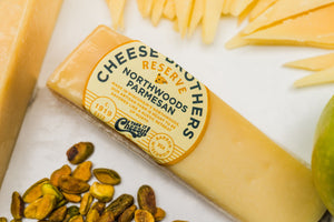 Zoomed in wedge of gourmet parmesan on a white charcuterie board. 