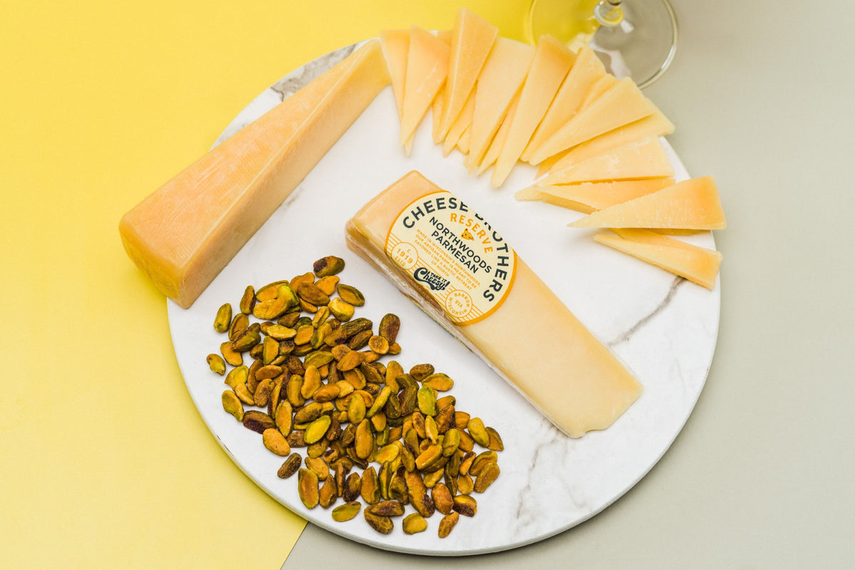 Wedge of gourmet parmesan on a white charcuterie board. 
