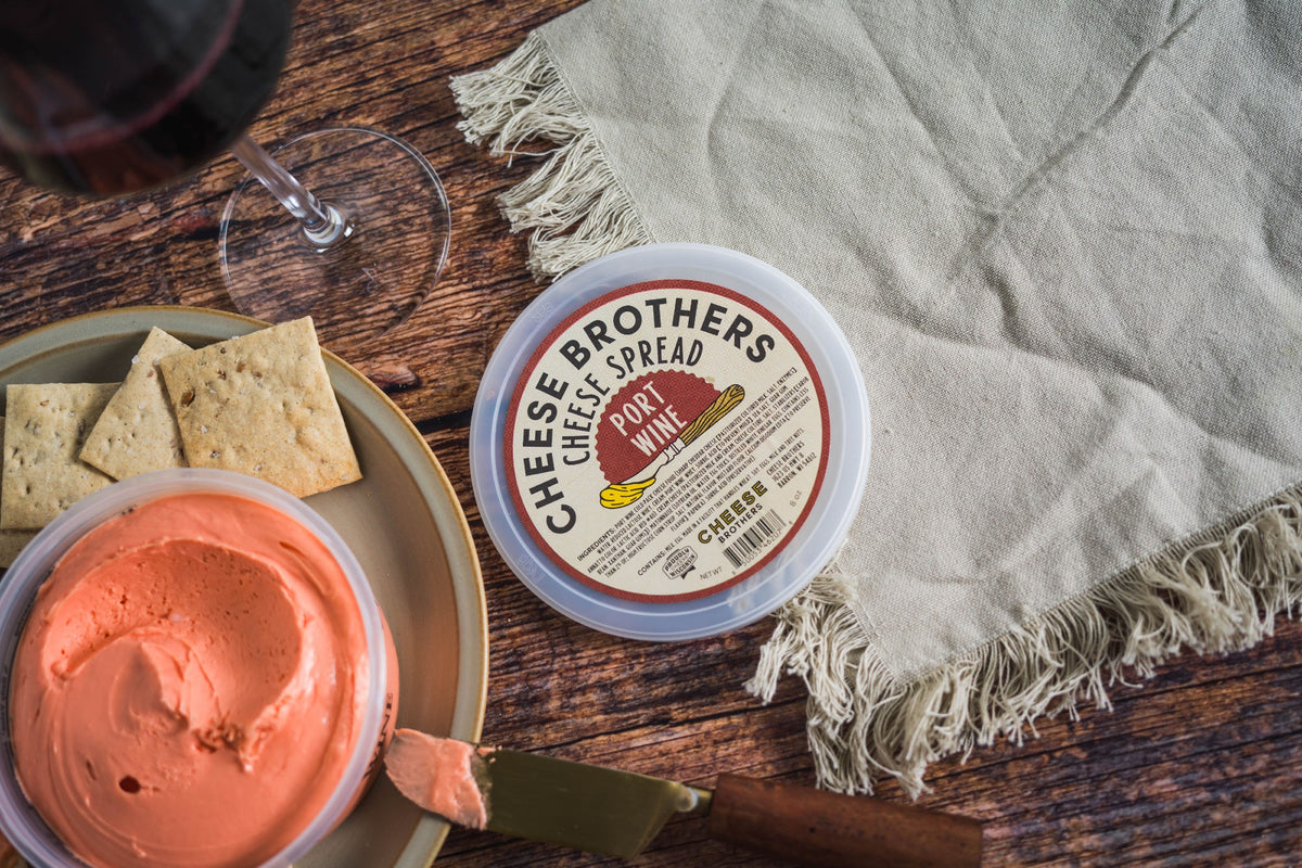 Container of port wine cheese spread with crackers and glass of wine. 