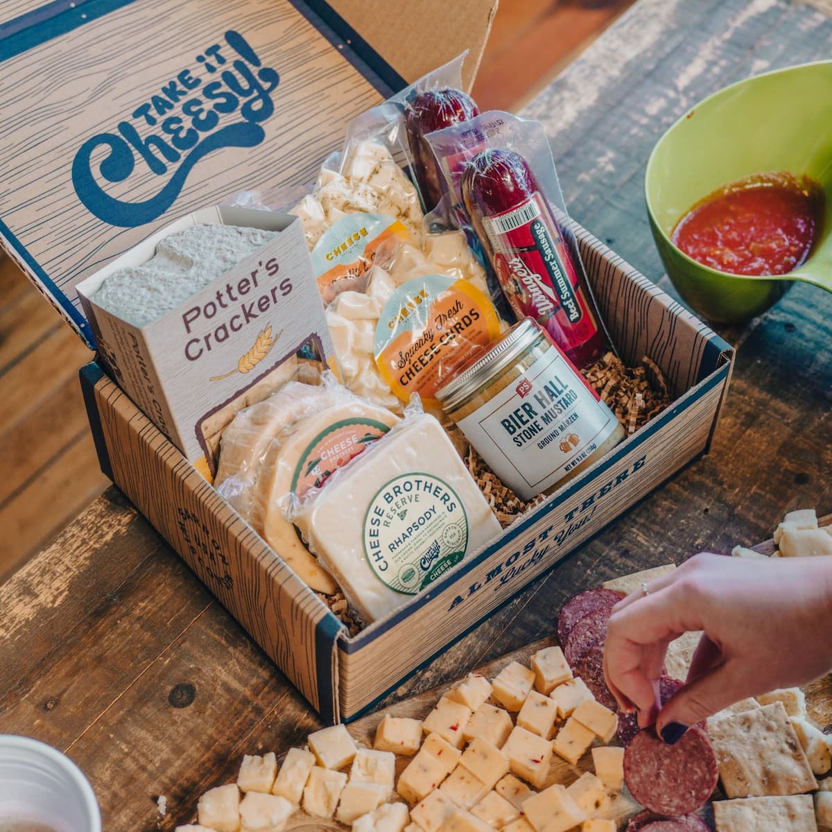 Selection of Cheese Brothers cheeses packed inside of a 'Take it Cheesy' box