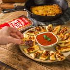 Slices of Baked Bliss cheese, placed on a plate around a bowl of soup.
