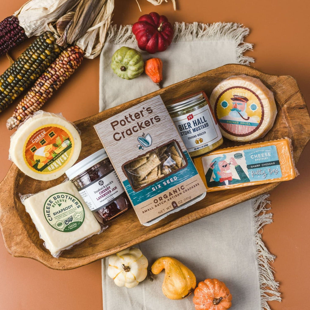Collection of 'Cheese Brothers' cheese and accompaniments together in a wooden bowl.