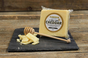 Package of 15-year aged Wisconsin white cheddar on black slate with cheese slices.