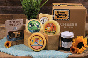Housewarming cheese box with four varieties of artisan cheeses, jam, and organic crackers. 