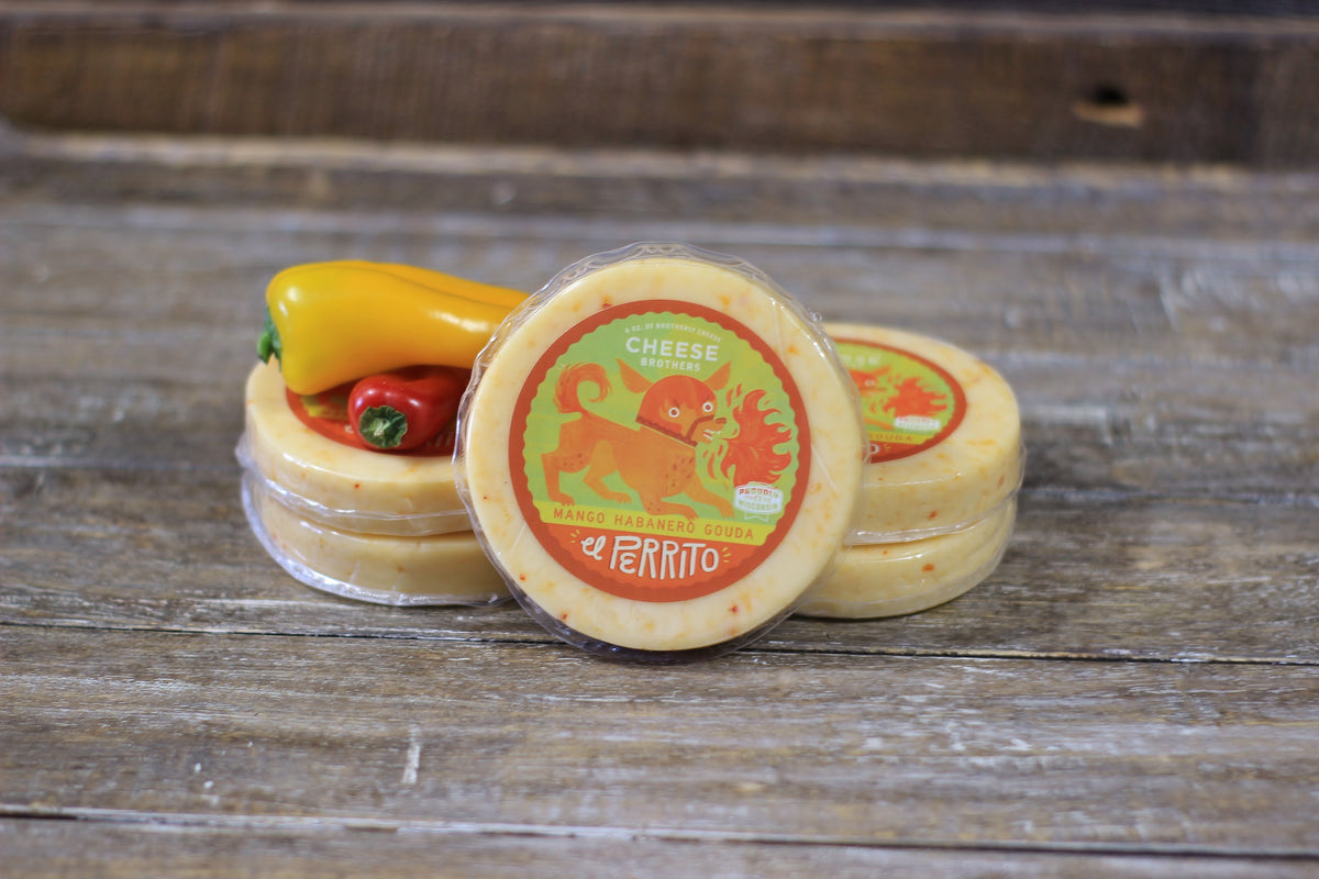 Packages of El Perrito - a mango habanero gouda on wooden table.