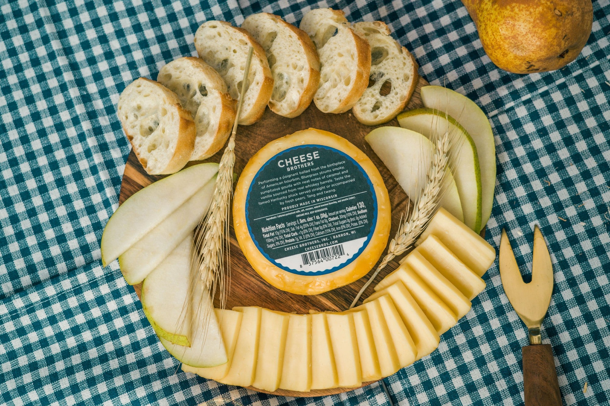 Package of Bluegrass bourbon gouda on board with bread, apples, and sliced cheese. 