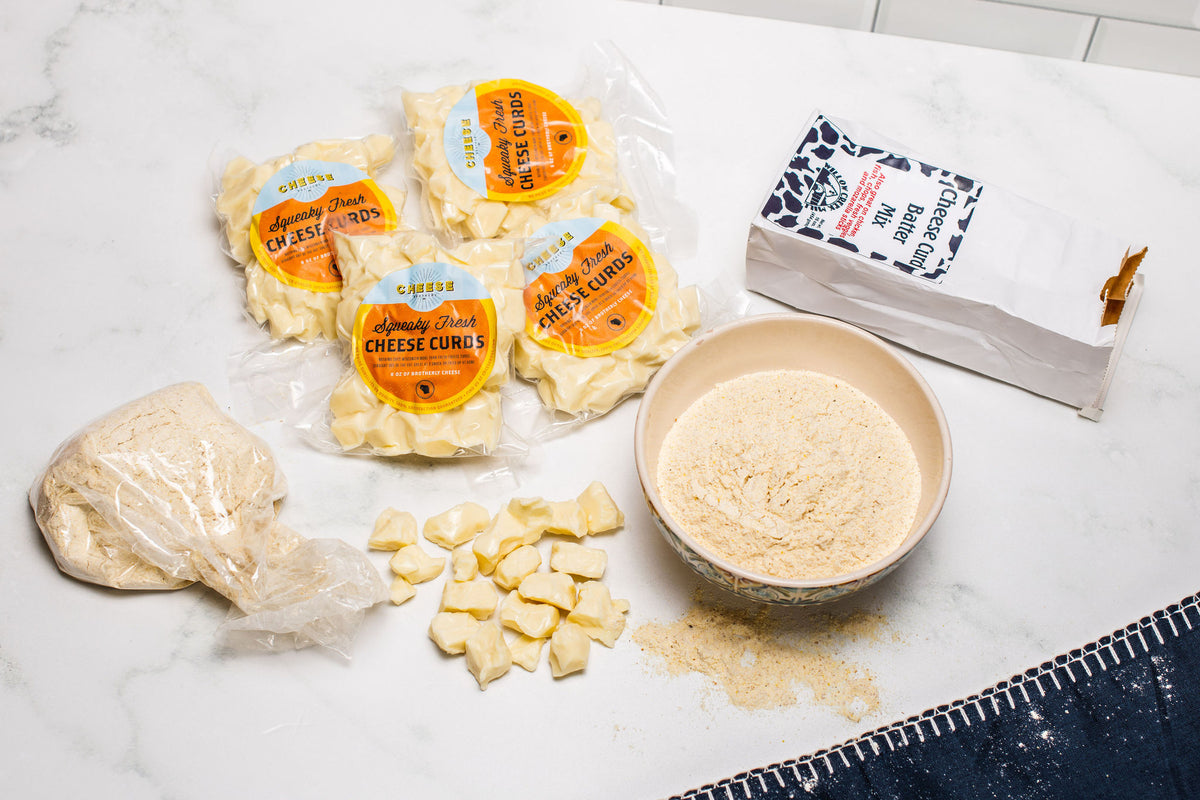 Packages of cheese curds, a bowl of batter, and open bag of cheese curd batter mix. 