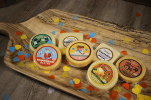 Seven varieties of artisan Wisconsin cheese from the thank you gift box on a wooden tray. 