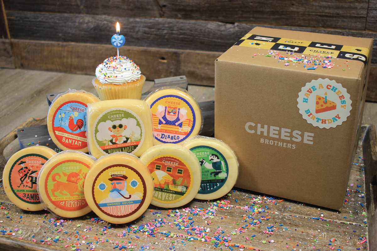 Birthday gift box with eight varieties of gourmet Wisconsin cheeses with birthday cupcake and candle. 
