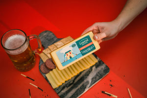 Cheese Brothers cinderblock smoked cheddar above a charcuterie board and glass of beer. 