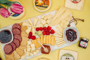 Deluxe Mother's Day charcuturie with salami, gourmet cheeses, jams, and honey surrounded by packages. 