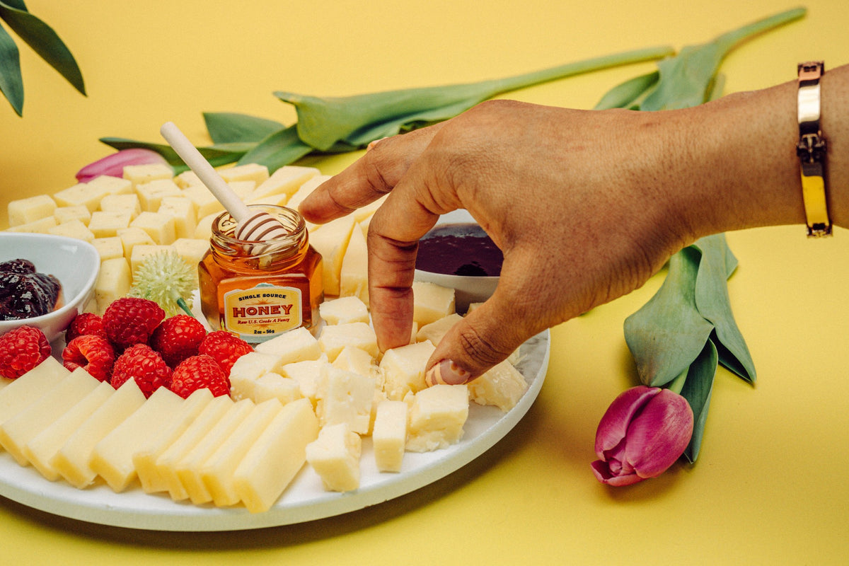 Hand picking up a cheese cube from charcuterie plate. 
