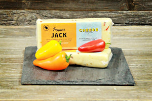 Package of gourmet pepper jack cheese on a black slate with peppers. 