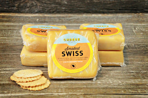 Package of artisan smoked swiss in front of stacks of cheese. 