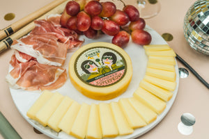 Package of artisan smoked provolone on a charcuterie board.