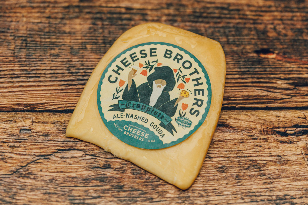 A package of ale-washed gouda on a wooden table. 