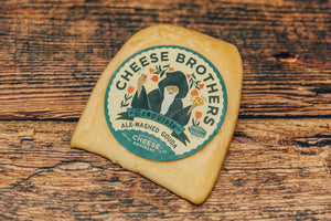 A package of ale-washed gouda on a wooden table. 