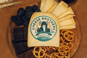 Package of ale-washed gouda on a plate with berries, pretzels, cheese slices, and chocolate. 