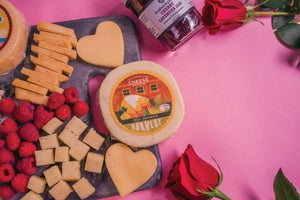 Valentines Day Charcuterie plate with a variety of gourmet cheeses, jam, berries, and roses.