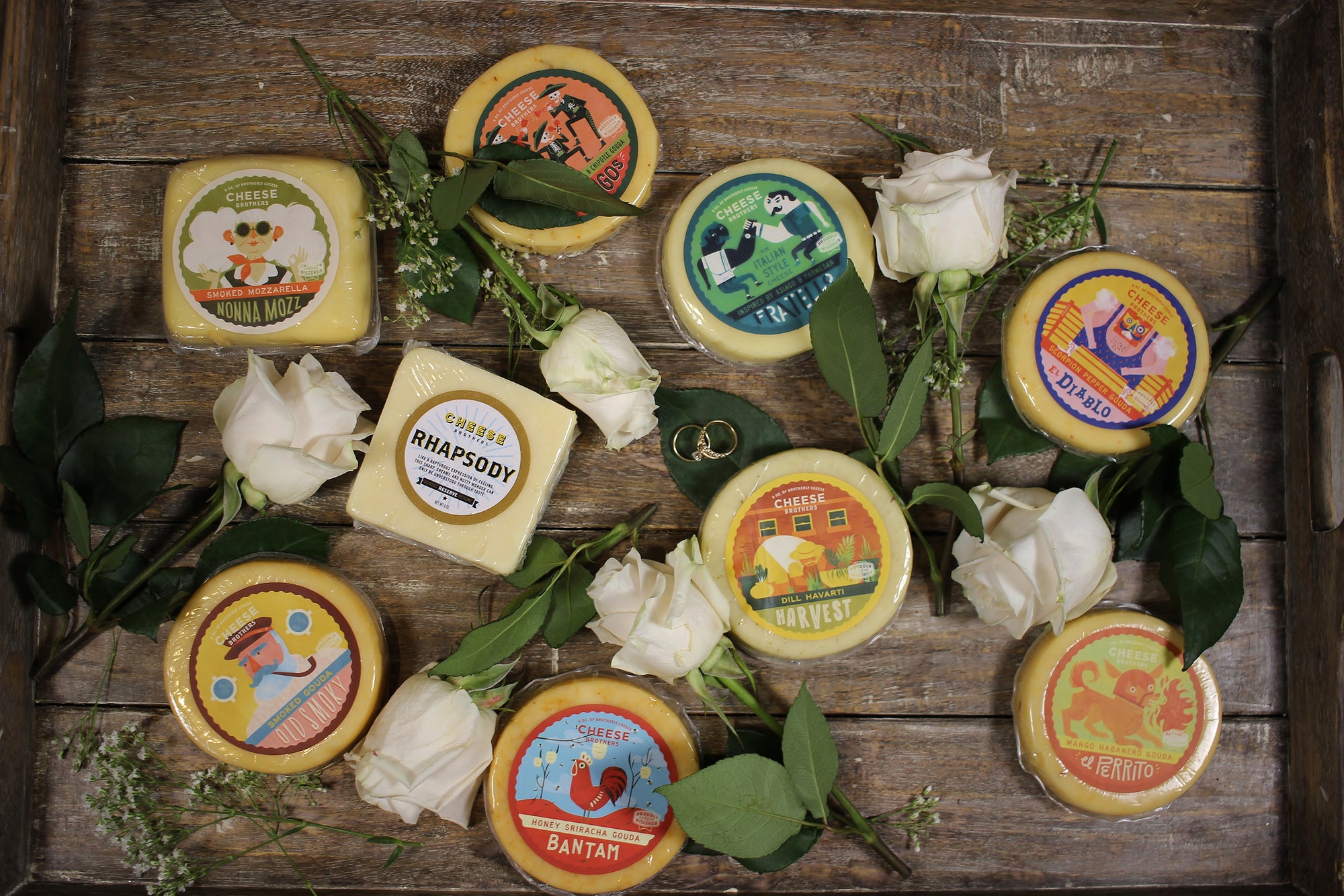 Wedding gift box with nine varieties of gourmet Wisconsin cheeses on a tray with white roses. 