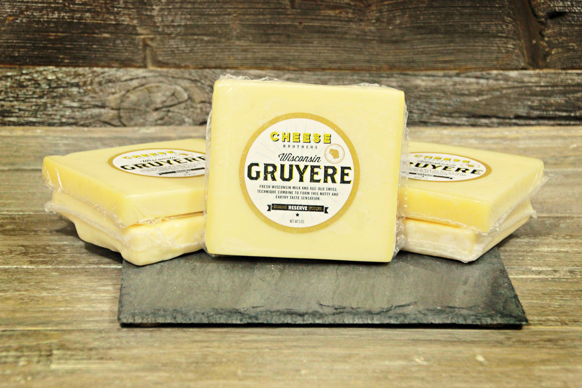 Packages of artisan Gruyere on a black slate. 